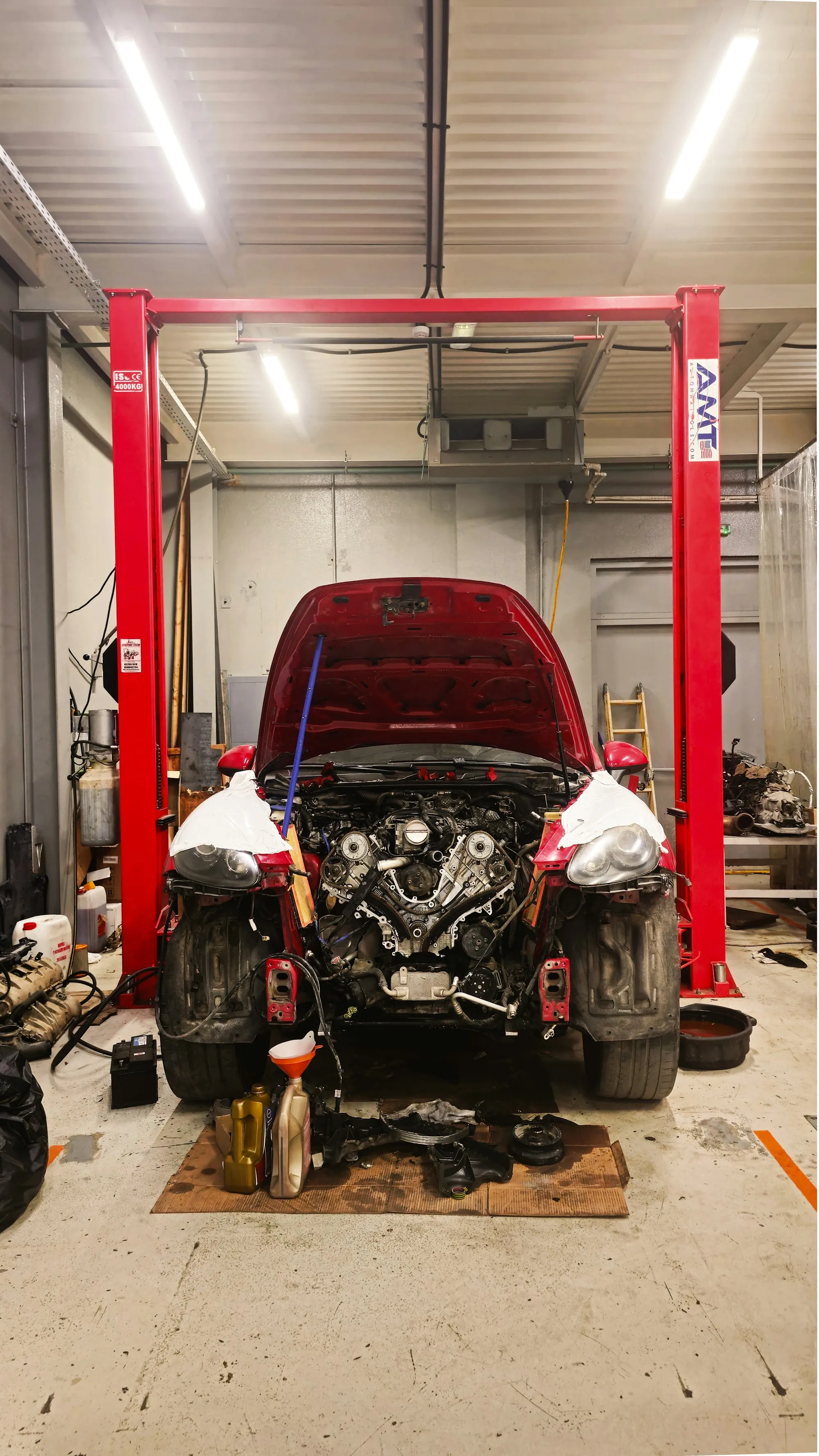 Mechanic leaning over the engine of a car on a lift