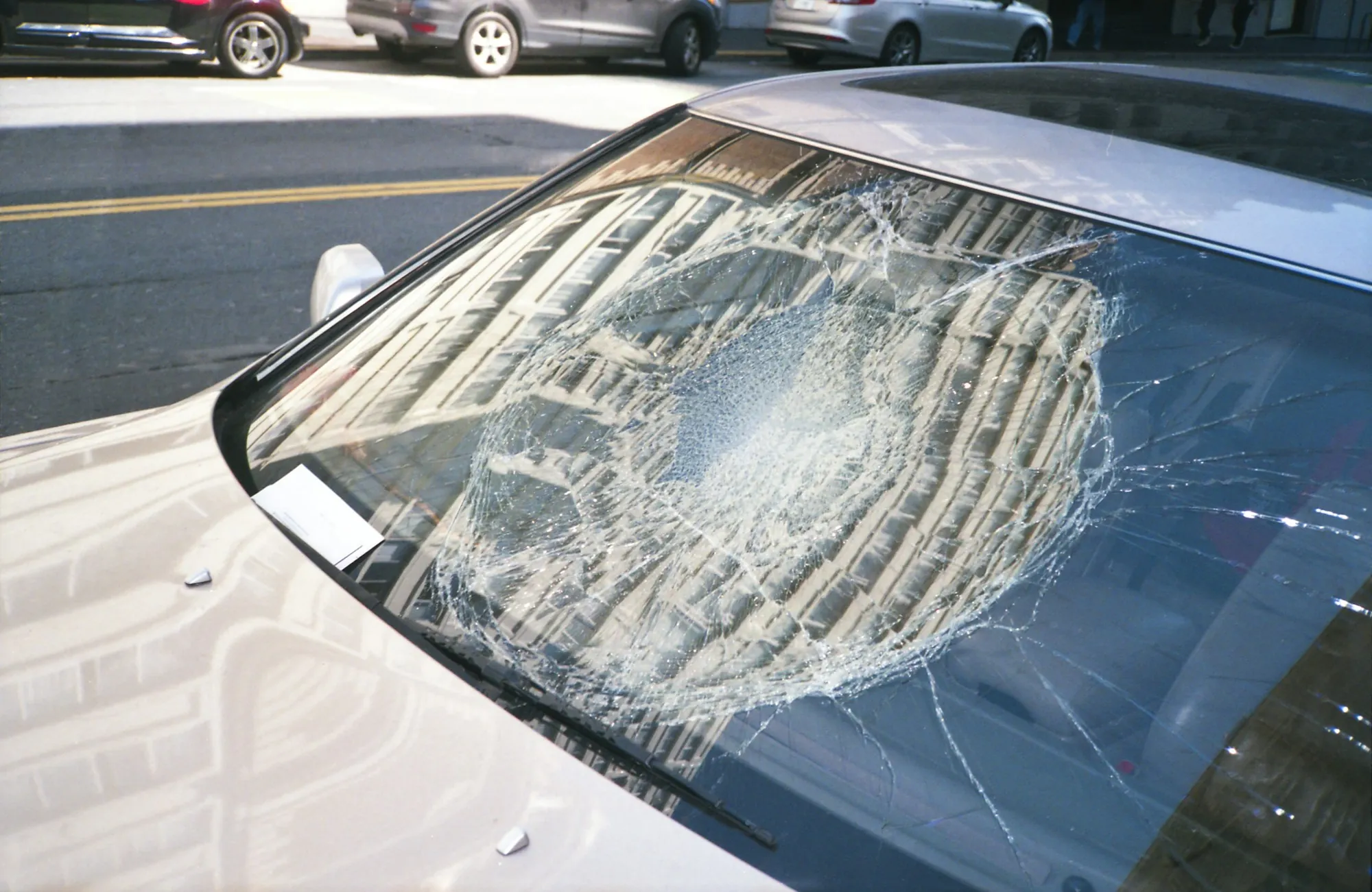 Technician setting a new windshield into a car frame with suction cup handles