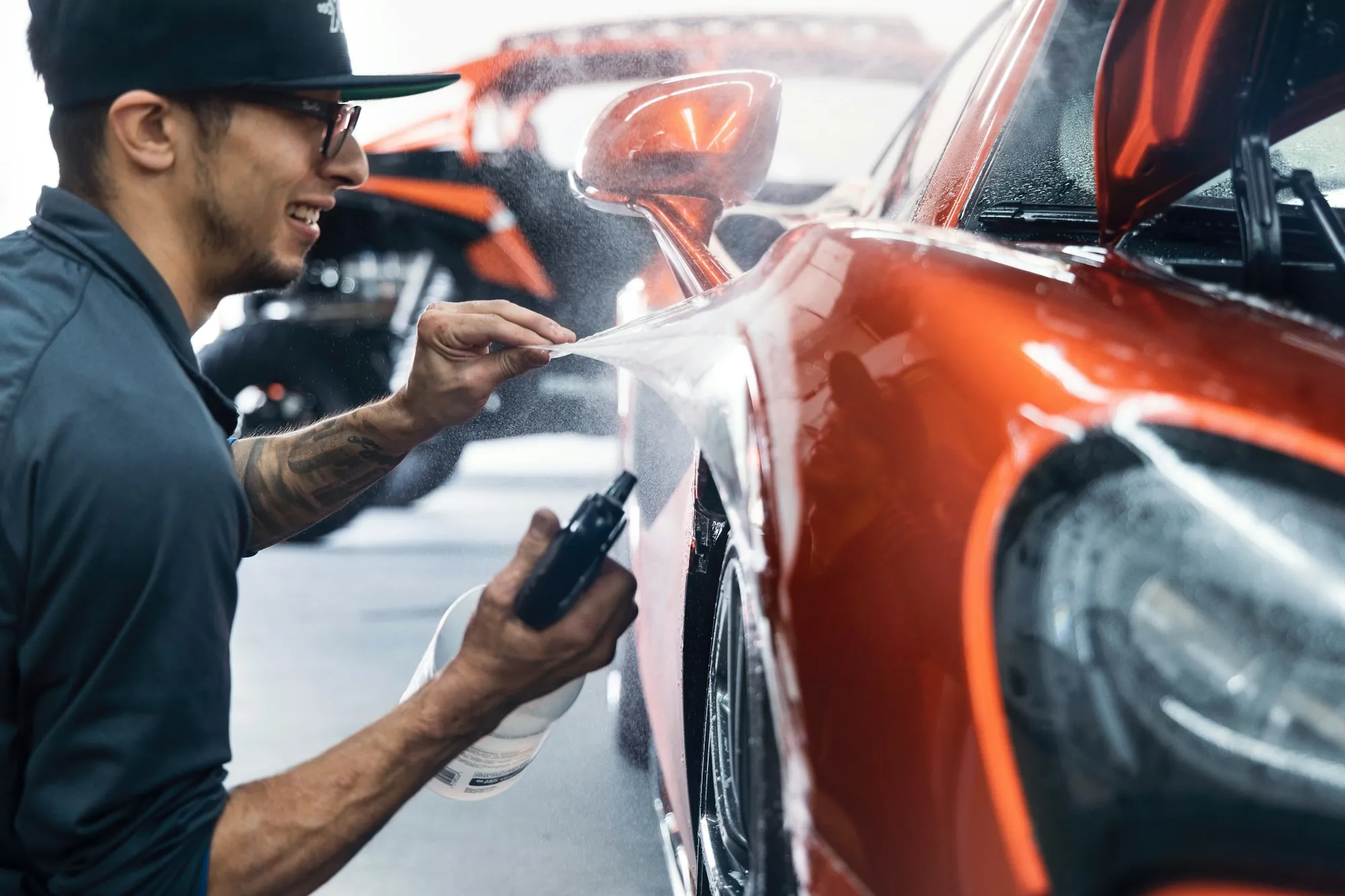 Person waxing an orange car inside a garage