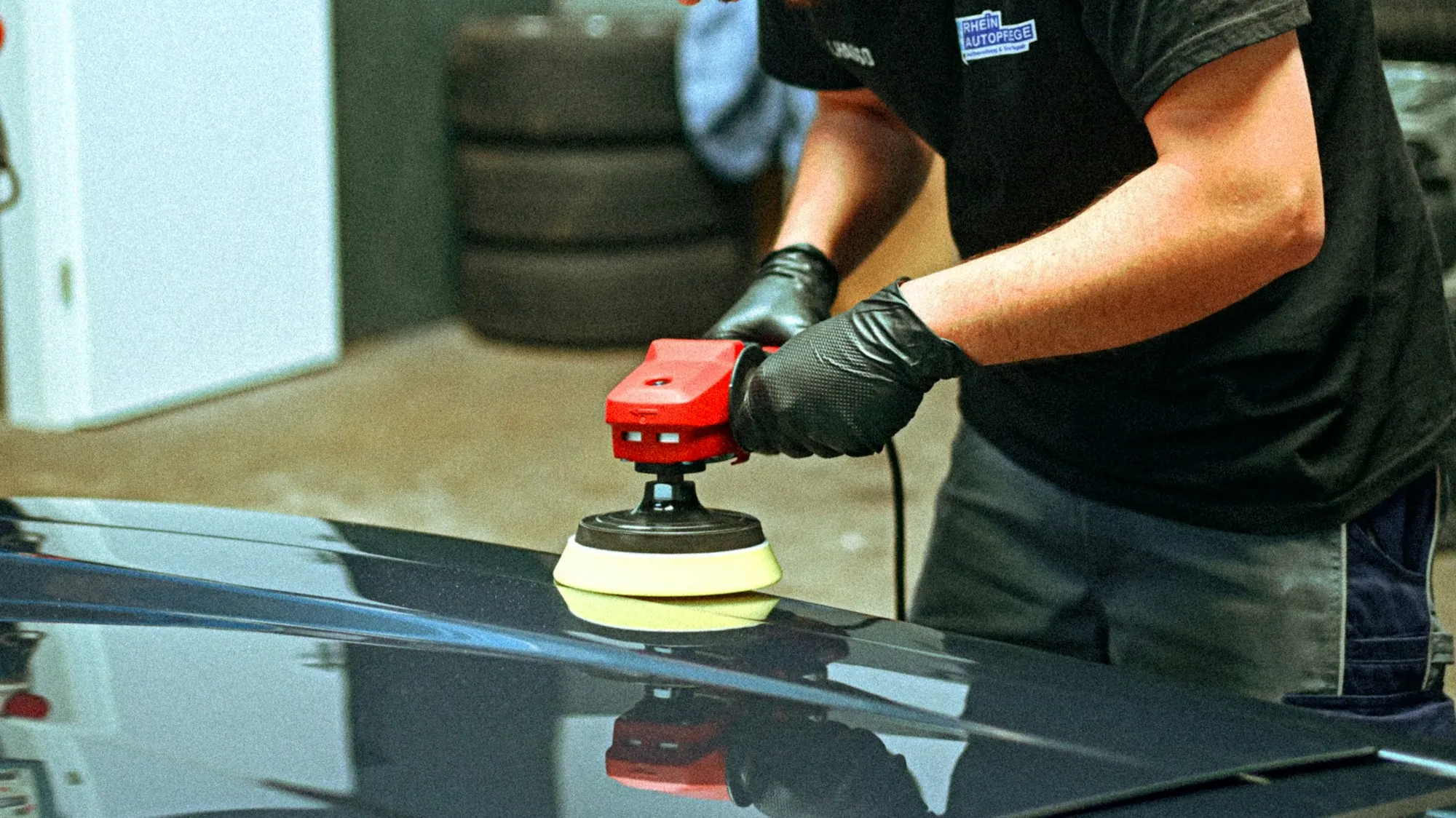Technician buffing the paint on a dark car