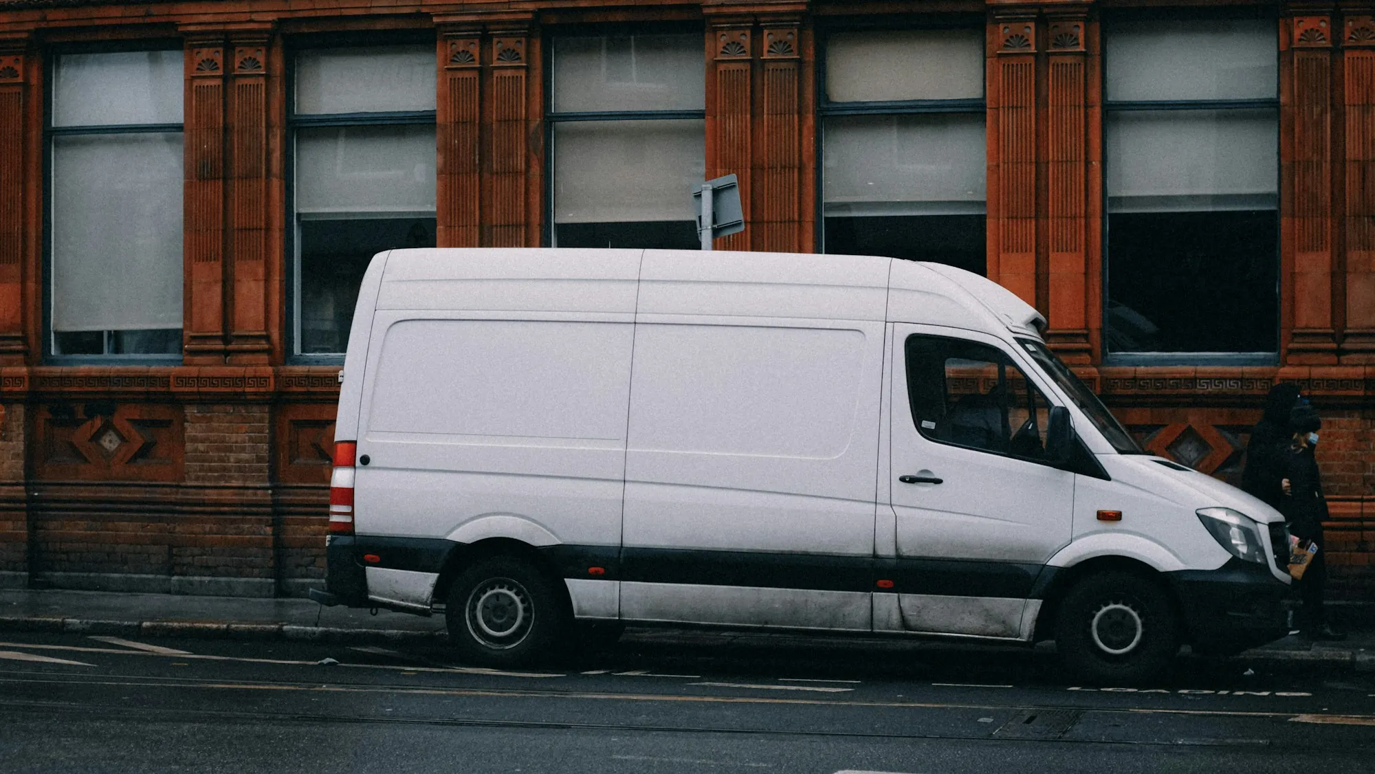 White cargo van with side panel damage parked in a body shop bay