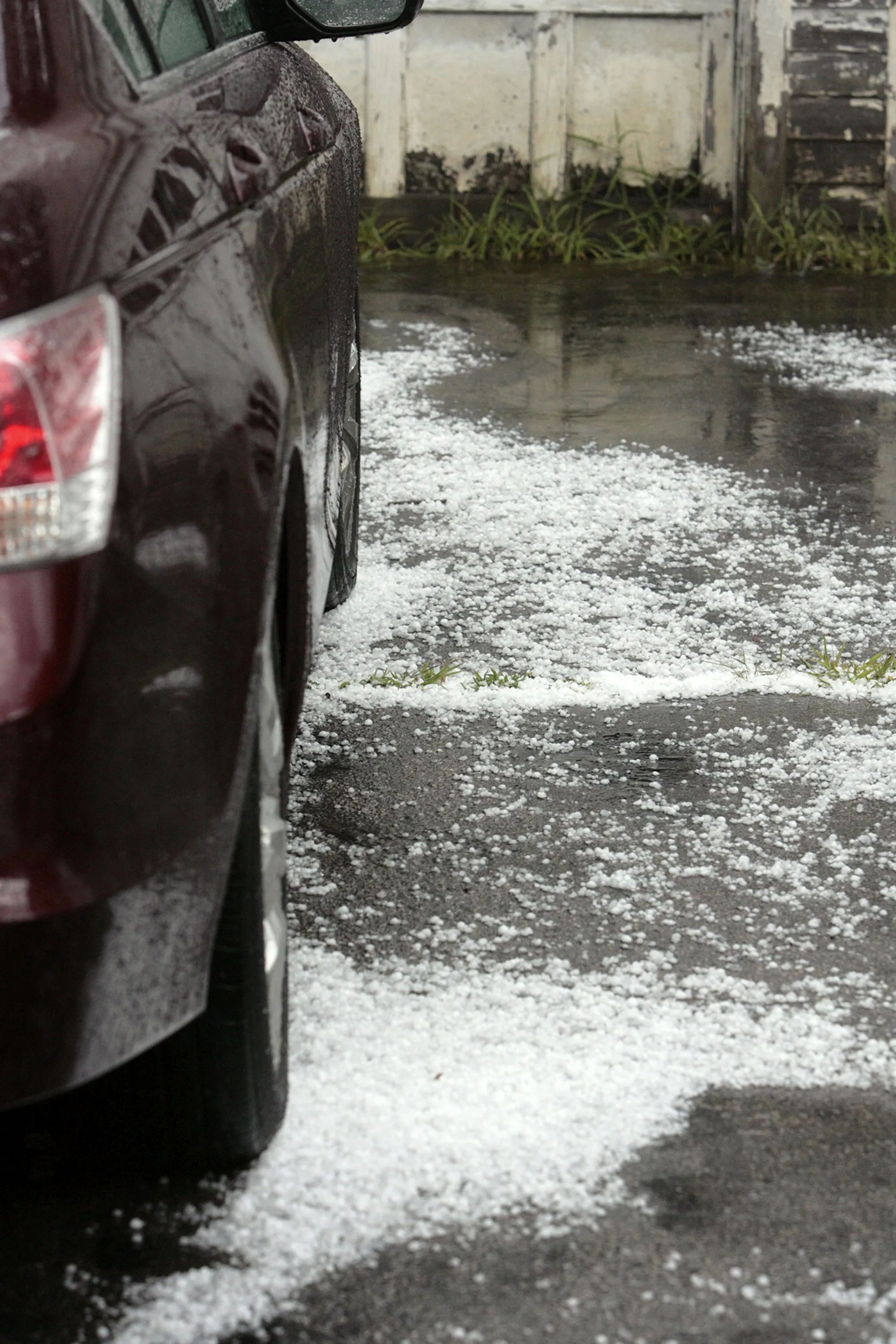 Gray SUV roof with rows of small hail dents under bright inspection lights
