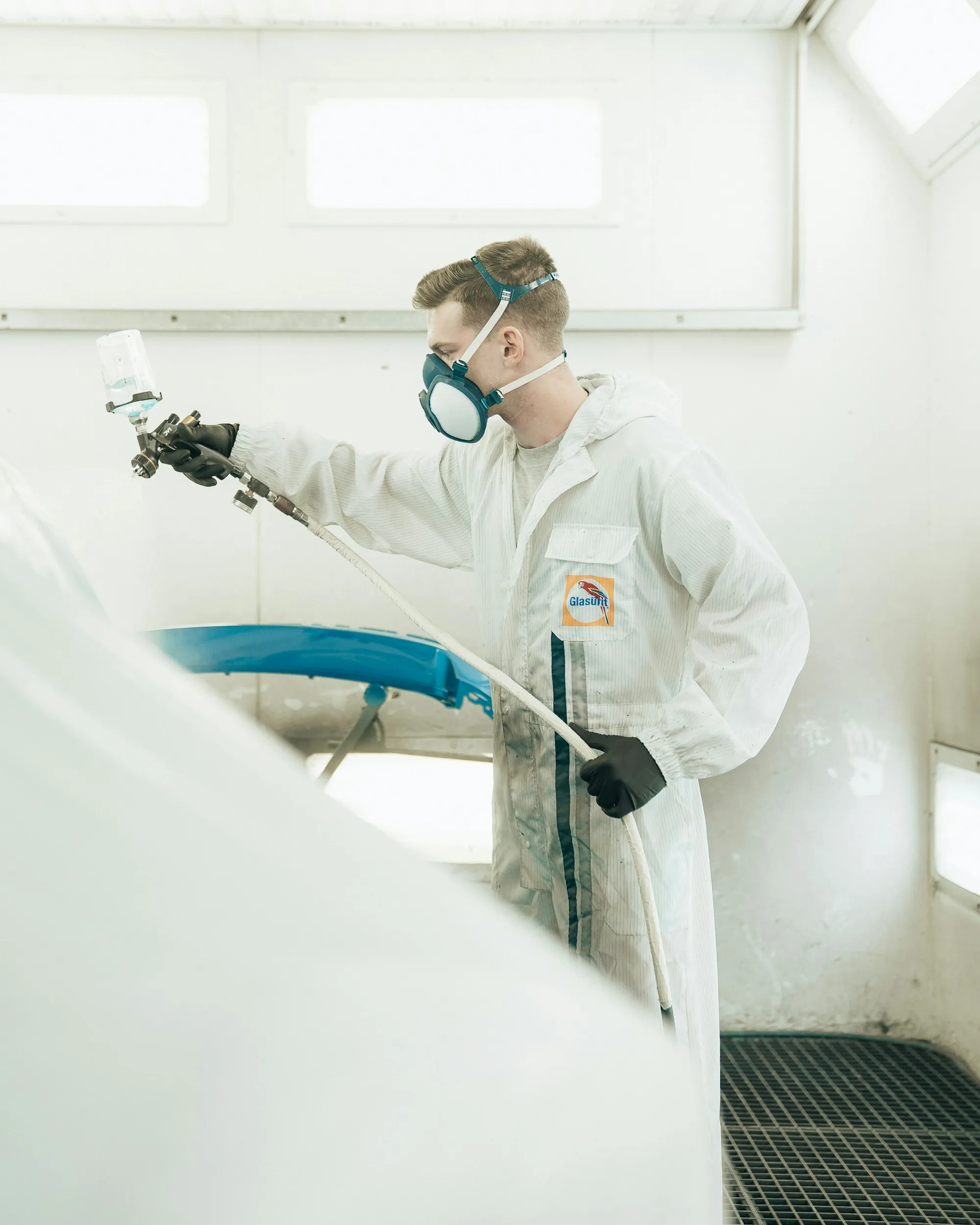 Painter spraying a fresh coat on a car hood
