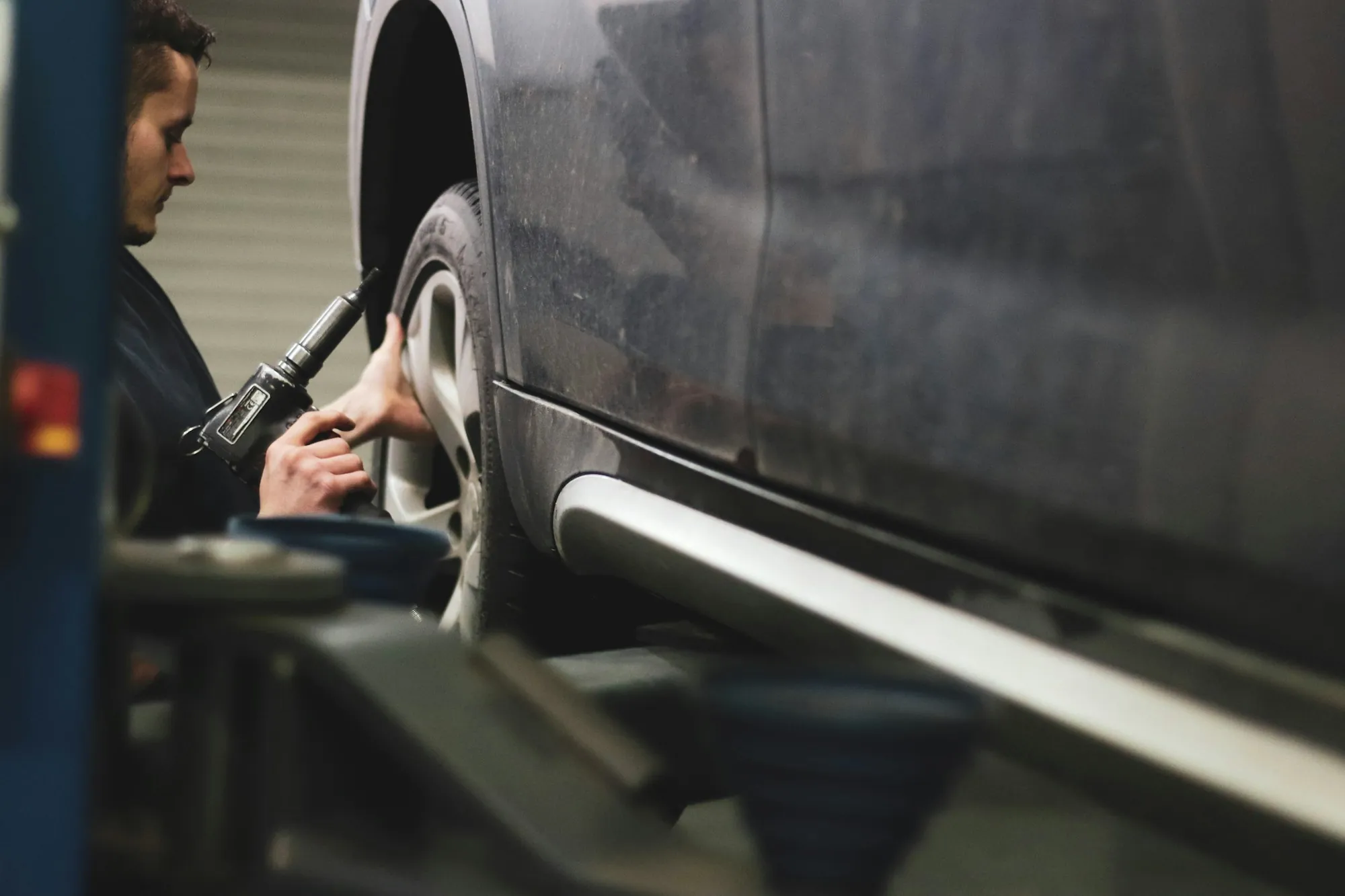 Technician inspecting a dark car in a repair bay
