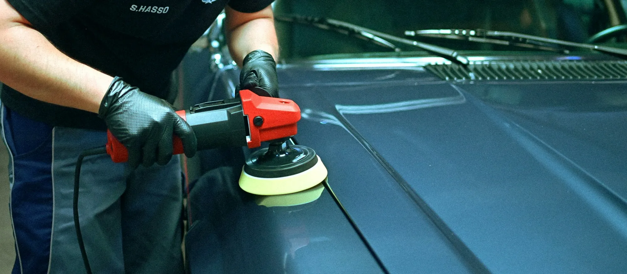 Technician using a striped light board to read a door ding on a black sedan