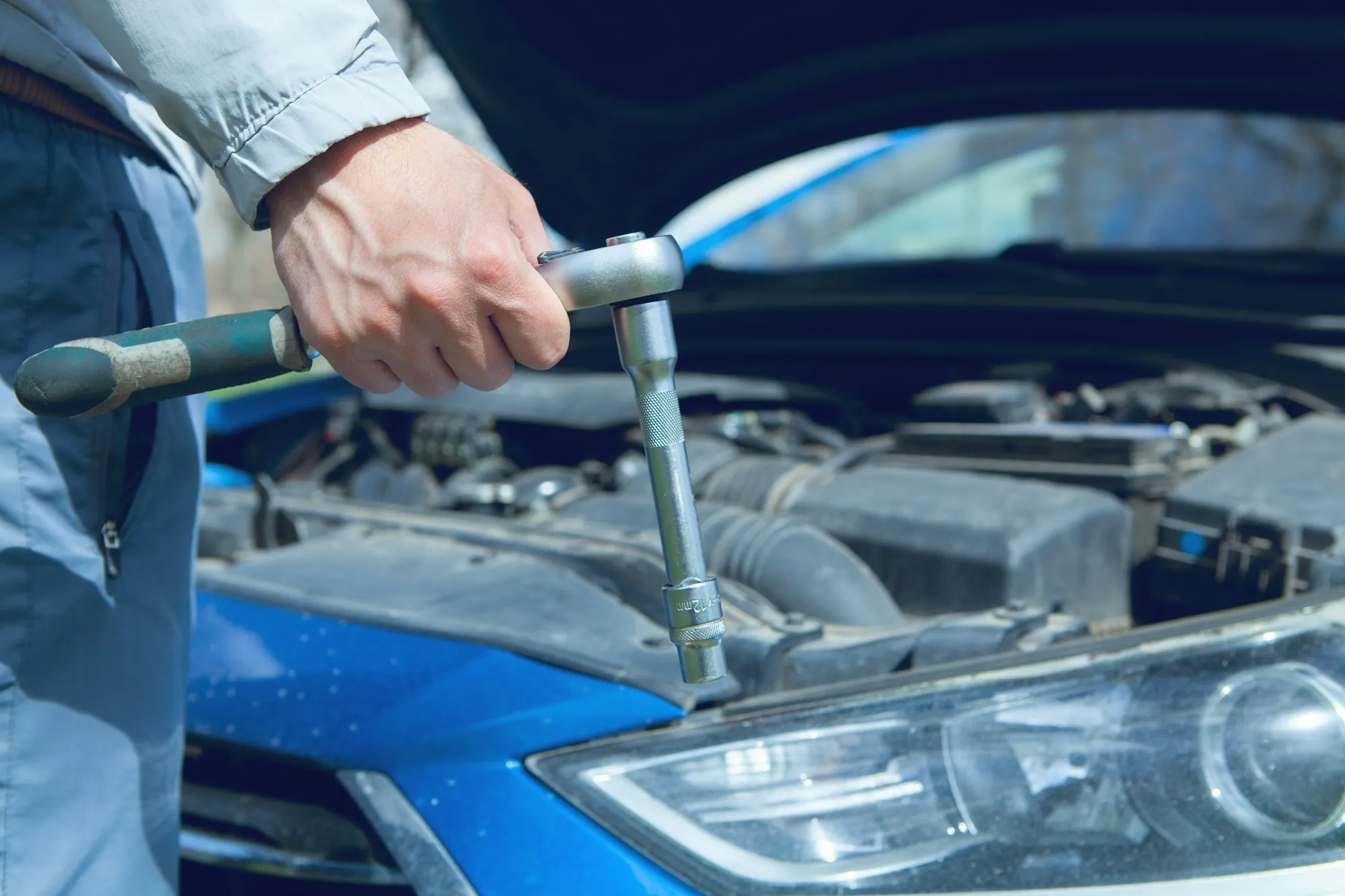 Mechanic using a wrench in a car's engine bay