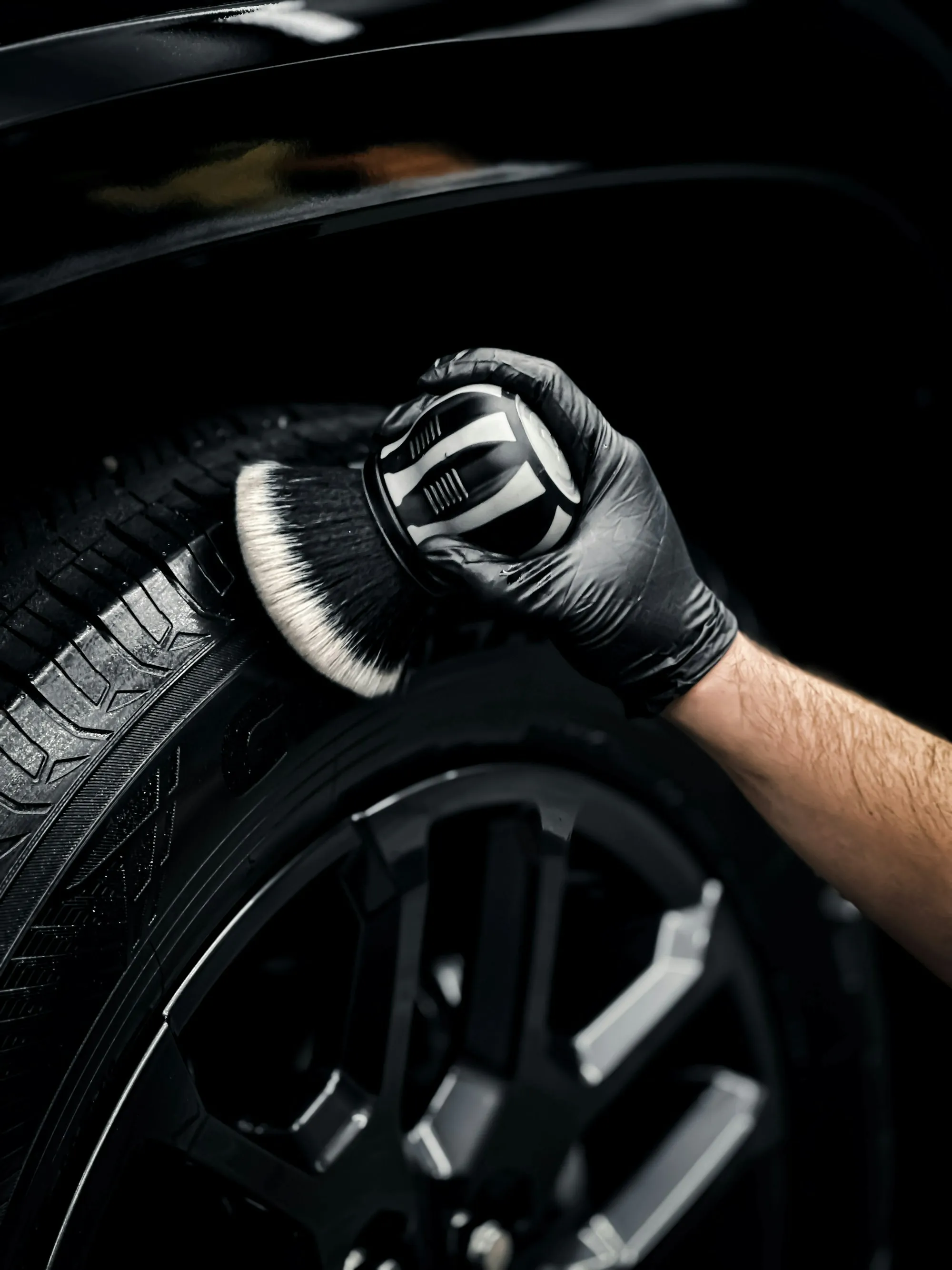 Gloved hand cleaning a car wheel
